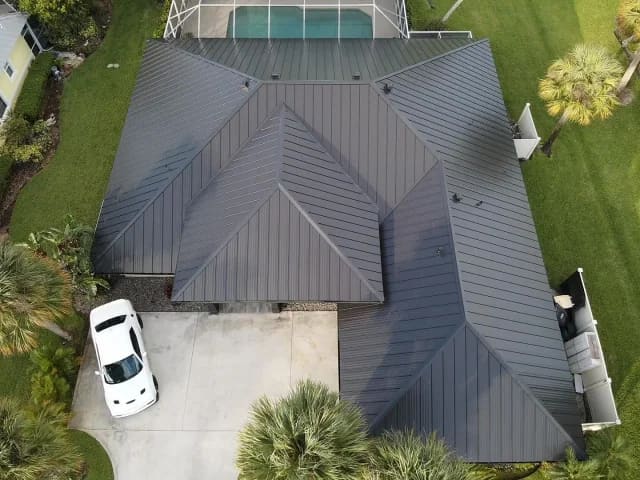 Overhead drone shot of a finished dark gray standing-seam metal roof.