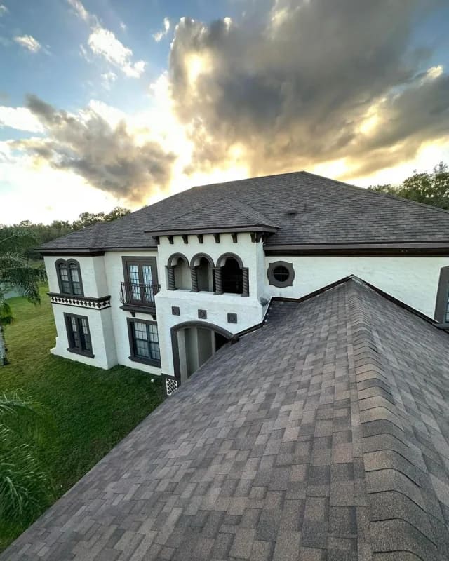 Two-story Mediterranean home with a freshly installed dark architectural shingle roof at sunset.