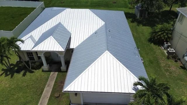 Drone view of a finished bright white standing-seam metal roof on a one-story Florida home.